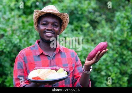 Afrikanischer Landwirt, der ein Gemüsepaket hält. Bio-Gemüse bereit, um in Salat Lieferservice zu dienen Stockfoto