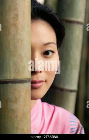 Nahaufnahme Porträt schöne junge asiatische Frau hinter Bambus Stockfoto
