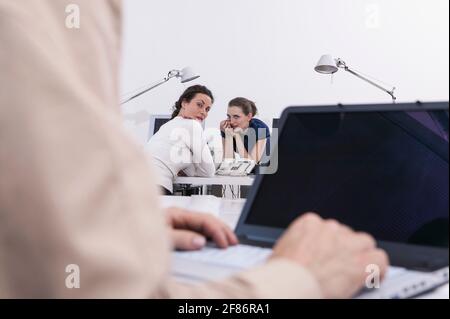 Geschäftsfrauen, die über Kollegen im Büro klatschen Stockfoto