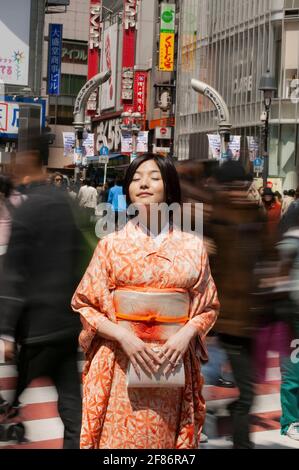 Ruhige junge Frau im Kimono in der sonnigen belebten Straße der Stadt Kyoto, Japan Stockfoto
