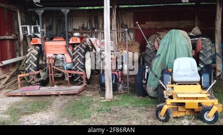 Mullion Creek NSW 2800, Australien. Old Village House's Garage .Two Traktoren und Rasen Mowners. Stockfoto