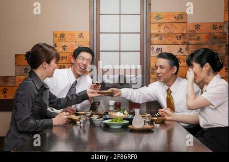 Glückliche japanische Geschäftsleute genießen Sushi-Mittagessen im Restaurant Stockfoto