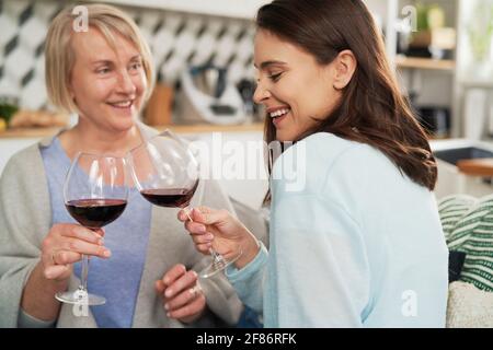 Glückliche Erwachsene Tochter und ältere Mutter, die in Wein toasten Stockfoto