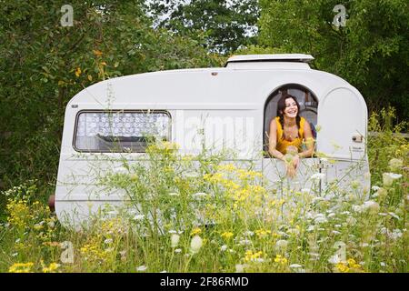 Glückliche junge Frau im Camper Trail auf der Wiese Stockfoto