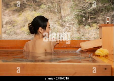 Junge Frau, die in der Onsen-Badewanne einweicht Stockfoto