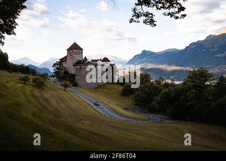 Sonnenaufgang auf Schloss Vaduz mit geschwungener Straße, blauem Himmel und grünem Wald (Vaduz, Fürstentum Liechtenstein, Europa) Stockfoto