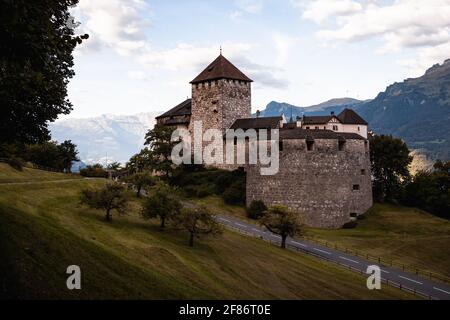 Sonnenaufgang auf Schloss Vaduz mit geschwungener Straße, blauem Himmel und grünem Wald (Vaduz, Fürstentum Liechtenstein, Europa) Stockfoto