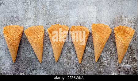 Flach Eistüten Sammlung auf dunklem Stein Hintergrund. Leere knusprige Eiswaffel mit Kopie Raum für Süßigkeiten Menü Design. Stockfoto