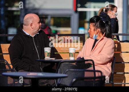 Newcastle upon Tyne, Großbritannien. April 2021. Zwei Personen unterhalten sich in den Old Eldon Gardens, Newcastle upon Tyne, bei einem Kaffee in der Sonne, da die nationalen Sperrbeschränkungen in England in Newcastle upon Tyne, England, am 4/12/2021 gelockert werden. (Foto von Iam Burn/News Images/Sipa USA) Quelle: SIPA USA/Alamy Live News Stockfoto