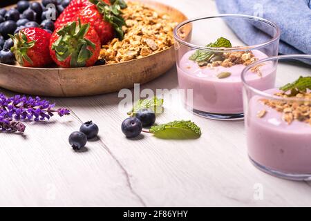 Natürlicher Joghurt mit frischen Beeren und Haferflocken. Gesundes Dessert.gesundes und natürliches Frühstück mit Heidelbeeren, Erdbeeren und Müsli mit Crea Stockfoto
