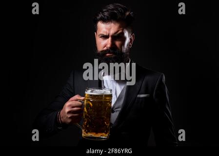 Porträt eines ernsthaften bärtigen Mannes, der Bier trinkt. Fröhlicher Brauer, der Glas mit Bier hält. Stockfoto