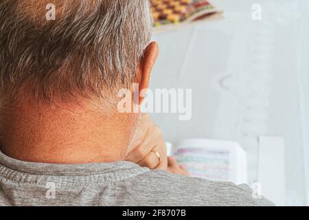 Der alte Mann liest Buch auf dem Tisch. Kulturelles Aktivitätskonzept mit einer Person. Stockfoto