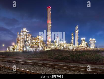 Nachtszene mit beleuchteter petrochemischer Produktionsanlage mit Bahngleisen im Vordergrund, Antwerpen, Belgien. Stockfoto