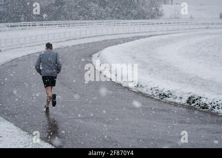 Epsom Downs, Großbritannien. April 2021. Ein Läufer im Schnee, der heute Morgen über die Surrey Hills fiel. Quelle: Edward Webb/Alamy Live News Stockfoto