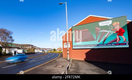 Greenock, Inverclyde, Schottland, Großbritannien. April 2021. IM BILD: Auf einer riesigen elektronischen Plakatwand zeigt Nicola Sturgeon, wie sie eine riesige Schere in einer Nachstellung der Dienstkürzungen ihrer Regierung im Royal Hospital von Inverclyde führt, nachdem sie versprochen hatte, sie zu behalten. Scotland Matters Pressemitteilung Link: https://www.scotlandmatters.co.uk/inverclyde-hospital-cuts-billboard-by-scotland-matters/ Bild: Colin Fisher/Alamy Live News Stockfoto