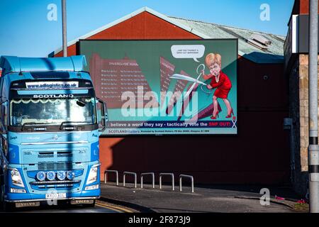 Greenock, Inverclyde, Schottland, Großbritannien. April 2021. IM BILD: Auf einer riesigen elektronischen Plakatwand zeigt Nicola Sturgeon, wie sie eine riesige Schere in einer Nachstellung der Dienstkürzungen ihrer Regierung im Royal Hospital von Inverclyde führt, nachdem sie versprochen hatte, sie zu behalten. Scotland Matters Pressemitteilung Link: https://www.scotlandmatters.co.uk/inverclyde-hospital-cuts-billboard-by-scotland-matters/ Bild: Colin Fisher/Alamy Live News Stockfoto