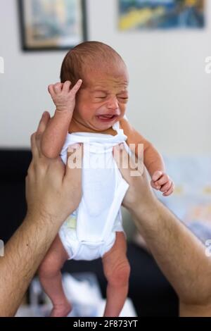 Weinendes Neugeborenes. Sehr niedlicher Junge in den Händen des Vaters Stockfoto