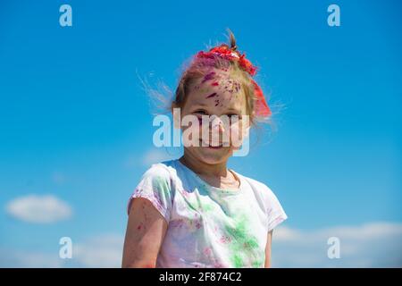 Kinder Holi Festival der Farben. Bemaltes Gesicht eines lächelnden Kindes. Kleines Mädchen spielt mit Farben. Stockfoto