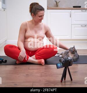 Sport zu Hause während der Schwangerschaft und Videoaufnahmen mit der Kamera. Schwanger Frau auf Fitness-Workout führt Online-Stream Stockfoto