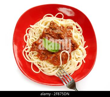 Spaghetti mit Tomatensauce auf rotem Teller mit Gabel, isoliert auf weißem Hintergrund Stockfoto