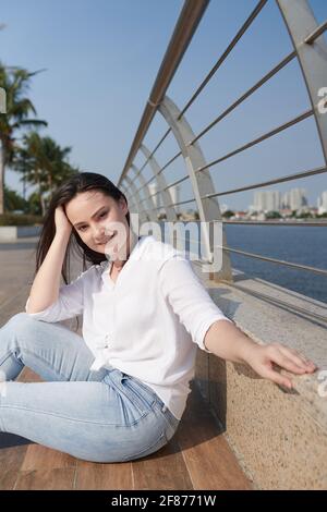 Porträt einer lächelnden schönen jungen Frau, die ihre Haare berührt und Blick auf die Kamera Stockfoto