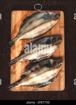 Roher Flunder Fisch, Meeresfrüchte auf einem hölzernen Schneidbrett . Gesunde Ernährung Konzept. Draufsicht Stockfoto