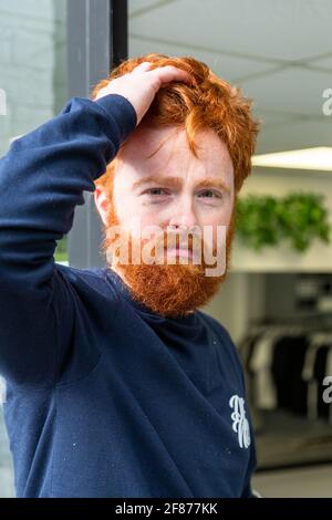 Halesowen, West Midlands, Großbritannien. April 2021. Firmenchef Rhys Barrett, 27, geht zu seinem Barbier in Halesowen, West Midlands, um einen willkommenen Haarschnitt und Bartschnitt zu erhalten, während sich die Barbiere nach der Lockerung der Covid-Beschränkungen heute öffnen. Kredit: Peter Lopeman/Alamy Live Nachrichten Stockfoto