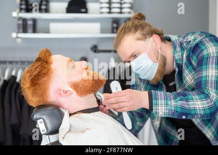 Halesowen, West Midlands, Großbritannien. April 2021. Firmenchef Rhys Barrett, 27, lässt sich von Sam Whitlock, Miteigentümer von Label Male Image in Halesowen, West Midlands, die Haare schneiden, da sich heute nach der Lockerung der Covid-Beschränkungen die Barber öffnen. Kredit: Peter Lopeman/Alamy Live Nachrichten Stockfoto