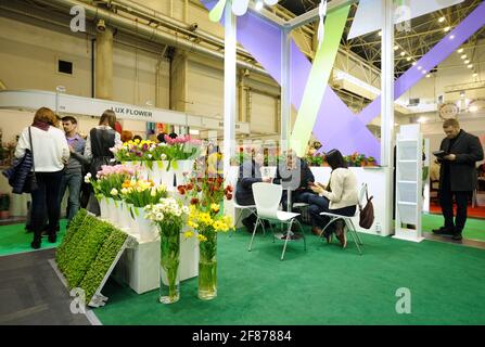 Menschen, die in einer Lounge-Zone zwischen Blumensträußen sitzen. 17. April 2019. Ausstellung Flower Expo Ukraine. Kiew, Ukraine Stockfoto
