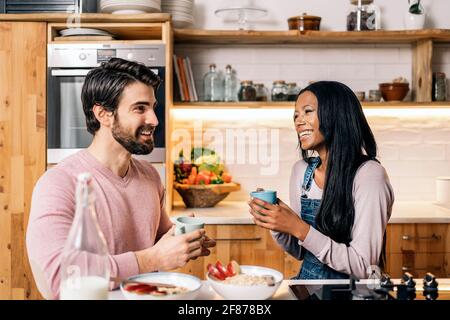 Fröhliche schwarze Frau und ihr Freund beim leckeren Frühstück in der Küche zu Hause. Stockfoto