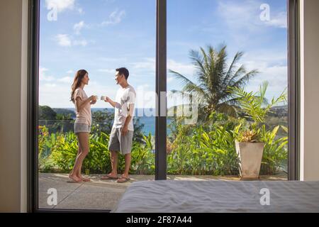 Glückliches junges Paar, das Kaffee auf dem Balkon trinkt Stockfoto