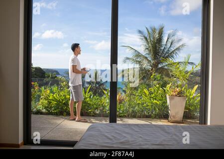 Glücklicher junger Mann, der Kaffee auf dem Balkon trinkt Stockfoto