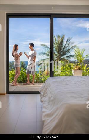 Glückliches junges Paar, das Kaffee auf dem Balkon trinkt Stockfoto