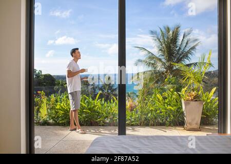 Glücklicher junger Mann, der Kaffee auf dem Balkon trinkt Stockfoto