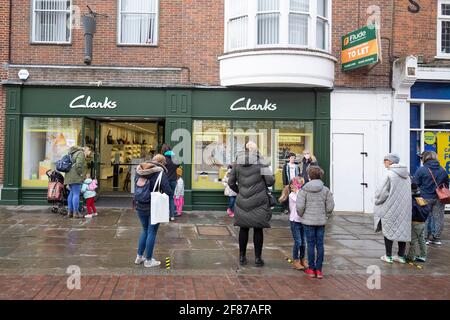 Chichester, Großbritannien. April 2021. Einkäufer stehen vor einem Clarkes Shoe-Shop Schlange, da der Einzelhandel und andere Unternehmen wieder geöffnet werden, da die Beschränkungen für die Sperrung durch England gelockert werden. Kredit: Paul Terry Foto/Alamy Live Nachrichten Stockfoto