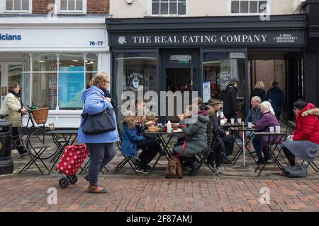 Chichester, Großbritannien. April 2021. Mitglieder der Öffentlichkeit genießen Erfrischungen außerhalb eines Cafés, da nicht unbedingt erforderliche Geschäfte und andere Unternehmen wieder geöffnet werden, da England Lockdown-Beschränkungen gelockert werden. Kredit: Paul Terry Foto/Alamy Live Nachrichten Stockfoto