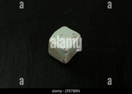 Zoisit, Saualpit oder auch der Rost im Wirtsgestein. Natürlicher Mineralstein auf schwarzem Hintergrund, umgeben von Moos. Mineralogie, Geologie, Magie, semi-kostbar Stockfoto