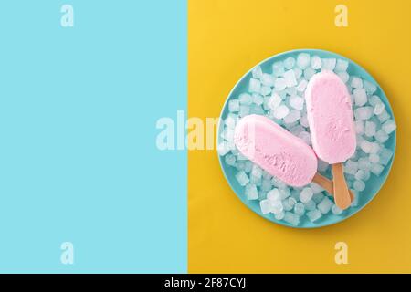 Erdbeerpopsicles und zerkleinertes Eis auf blauem Teller und gelb Und blauer Hintergrund Stockfoto