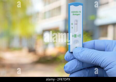 Die Hand hält Schnelltests im Freien, da das Büro-, Schul- oder Kindergartengebäude nicht im Fokus steht. Express COVID19-Test, Schnelltest ist ein schneller Corona-Test in Stockfoto