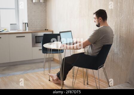 Junger männlicher Profi, der am Schreibtisch sitzt. Viel freier Mitarbeiter, der zu Hause arbeitet Stockfoto