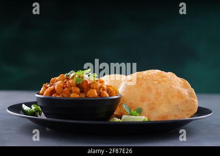 Indisches Frühstück  Poori mit Kichererbsenchana Masala, leckerem indischem Gericht Hergestellt aus Allzweck-Weizenmehl, das in angeordnet ist Eine schwarze Platte mit Stockfoto