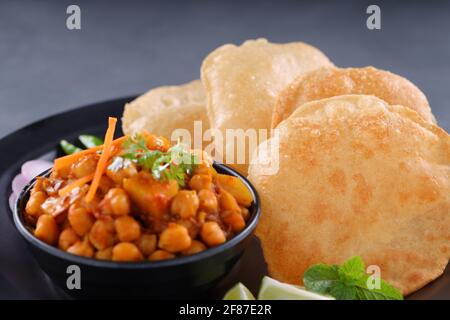 Indisches Frühstück  Poori mit Kichererbsenchana Masala, leckerem indischem Gericht Hergestellt aus Allzweck-Weizenmehl, das in angeordnet ist Eine schwarze Platte mit Stockfoto