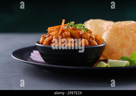 Indisches Frühstück  Poori mit Kichererbsenchana Masala, leckerem indischem Gericht Hergestellt aus Allzweck-Weizenmehl, das in angeordnet ist Eine schwarze Platte mit Stockfoto