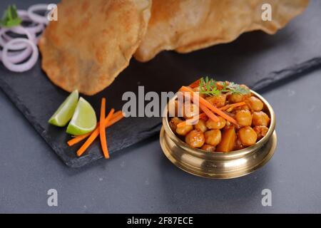 Ndianisches Frühstück  Poori mit Kichererbsenchana Masala-indische Küche Hergestellt aus Allzweck-Weizenmehl und Chana-Purpurpulver arrangiert In einer Messingvesse Stockfoto