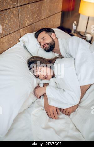 Ein Paar in weißen Bademänteln schläft und sieht friedlich aus Stockfoto