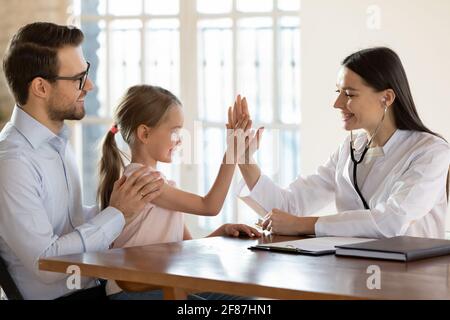 Lächelndes kleines Kind geben hohe fünf zu fürsorgliche Ärztin Stockfoto