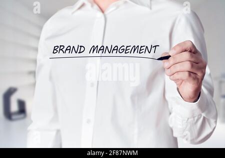 Businessman Hand hält einen Stift und unterstreicht die Worte Markenmanagement auf dem virtuellen Bildschirm. Geschäftsmarketing-Konzept. Stockfoto