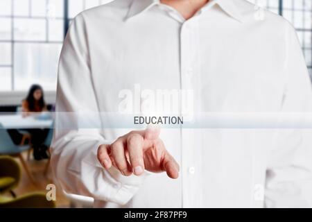 Männliche Hand drückt auf einem virtuellen Touchscreen die Bildungstaste. Stockfoto