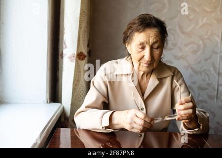 Eine sehr alte Frau zieht eine Brille an und schaut zu Die Kamera Stockfoto