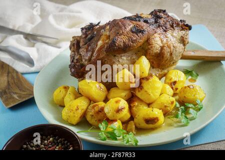 Ganze gebackene Schweineschulter mit gebratenen Baby-Kartoffeln und Gewürzen Auf der Platte Stockfoto